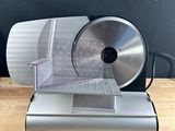 an image of a meat slicer sitting on top of a wooden table