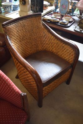 a wicker chair with a leather seat in a room