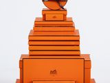 une image représentant une pile de cartons orange surmontée d'une horloge