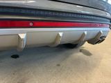 the rear end of a silver car with a red tail light
