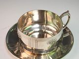 a silver cup and saucer sitting on a saucer