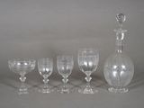 five wine glasses and a decanter sitting on a table