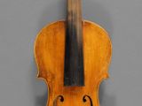 an old violin with a wooden back and bow on a gray background