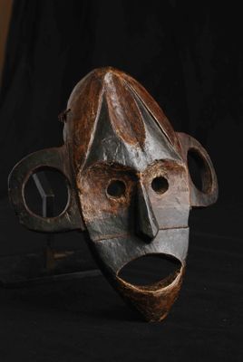 une image d'un masque en bois sur fond noir
