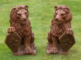 two statues of lions that are sitting in the grass