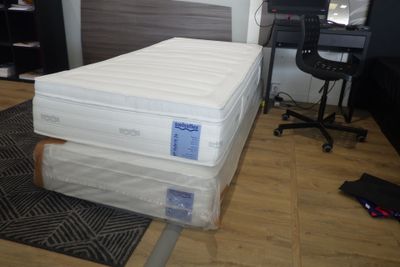 Des cartons contenant des matelas sont empilés les uns sur les autres dans une pièce
