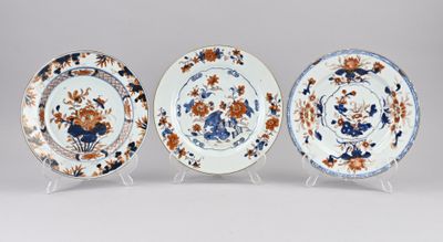 trois assiettes bleues et blanches ornées de fleurs orange, posées sur un présentoir
