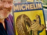 smiling man holding up a michel tire sign in a store