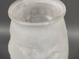 a glass vase with a bird on it on a table