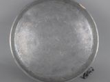 an old silver plate with a handle on a white surface