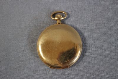 une image représentant une montre de poche en or posée sur un tissu bleu
