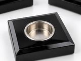 trois plats carrés noirs sur lesquels est posé un bol en argent
