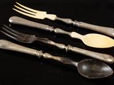 four forks and a spoon on a black table