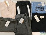 Plusieurs chemises et pantalons pour hommes sont exposés dans une vitrine.