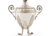 une coupe ancienne en métal argenté, munie d'une anse et posée sur un socle