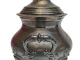 a small metal pot with a bird on top of it