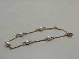 a gold chain bracelet with pearls on a white background