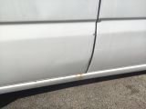 the side of a white van with rust on the side of it