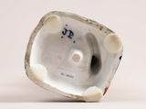 underside view of a porcelain figurine of a man holding a fish