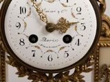 a gold clock with a white face and numbers on it
