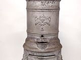 a small metal pot sitting on a stand on a marble floor