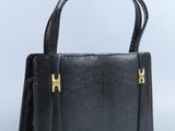 un sac à main noir avec des anses dorées sur fond blanc