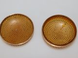 pair of gold plated buttons with holes on them sitting on a white surface