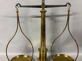 une balance en laiton sur laquelle sont posés deux plateaux vides