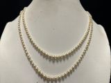 a close up of a necklace with pearls on a mannequin