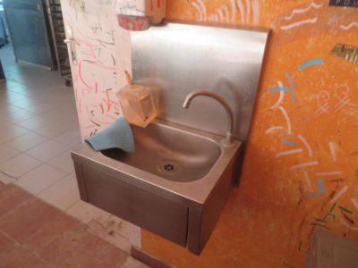 un lavabo dans des toilettes publiques, avec des graffitis sur les murs