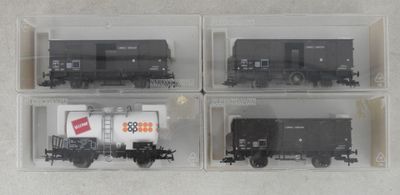 quatre wagons en noir et blanc dans des boîtes transparentes, posés sur une surface blanche