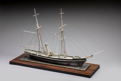 une image représentant une maquette de bateau posée sur un socle en bois