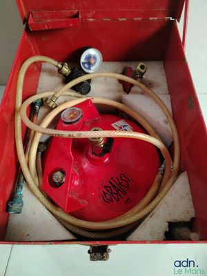 a red box that has a hose and a red canister in it