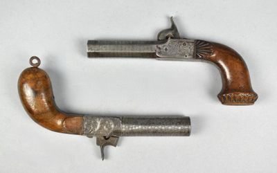 deux vieux pistolets à crosse en bois posés sur une surface blanche