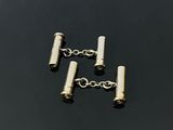 a close up of a pair of silver cufflinks on a black surface