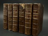 quatre vieux livres sont empilés les uns sur les autres sur une surface noire