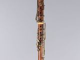 a clarinet with a wooden body and brass hardware on a clear base
