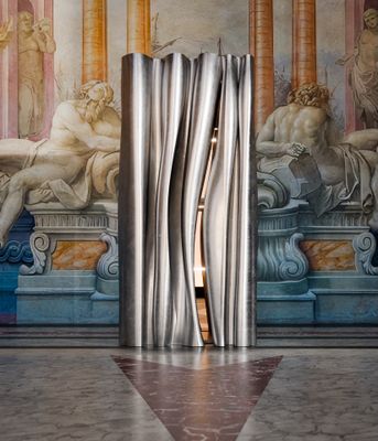 une photo d'une sculpture dans une pièce, avec un tableau accroché au mur derrière elle