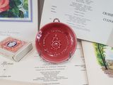 a red bowl sitting on top of a table next to a book