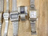 several watches are lined up on a table with a wooden table in the background