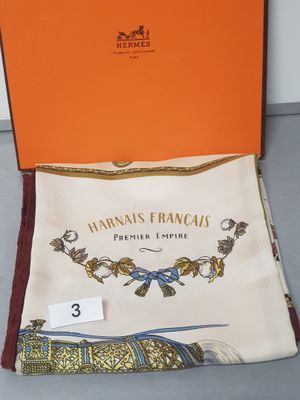 an orange box containing a scarf and a handkerchief with a picture of a bird on it