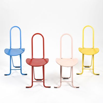 trois chaises de couleurs différentes placées côte à côte sur une surface blanche