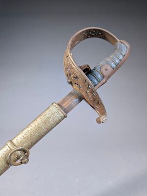 a very old sword with a metal handle on a gray surface