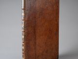 un vieux livre avec une couverture en cuir marron sur fond gris