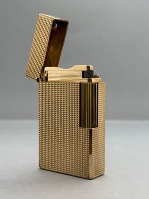 un gros plan d'un briquet doré posé sur une surface blanche