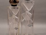 two bottles of perfume sitting next to each other on a gray surface