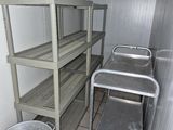 une petite pièce avec une étagère en métal et un seau en métal