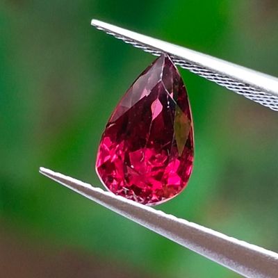 a close up of a pink diamond being held by a pair of pliers