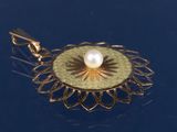 un pendentif en or serti d'une perle, sur un fond bleu
