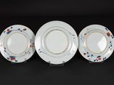 three plates with floral designs on them on a black surface